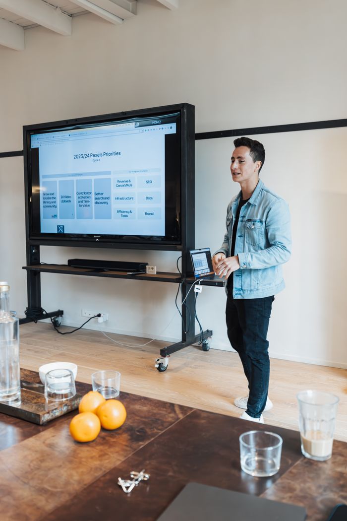 Man presenting business plans on screen in a casual meeting room setting.